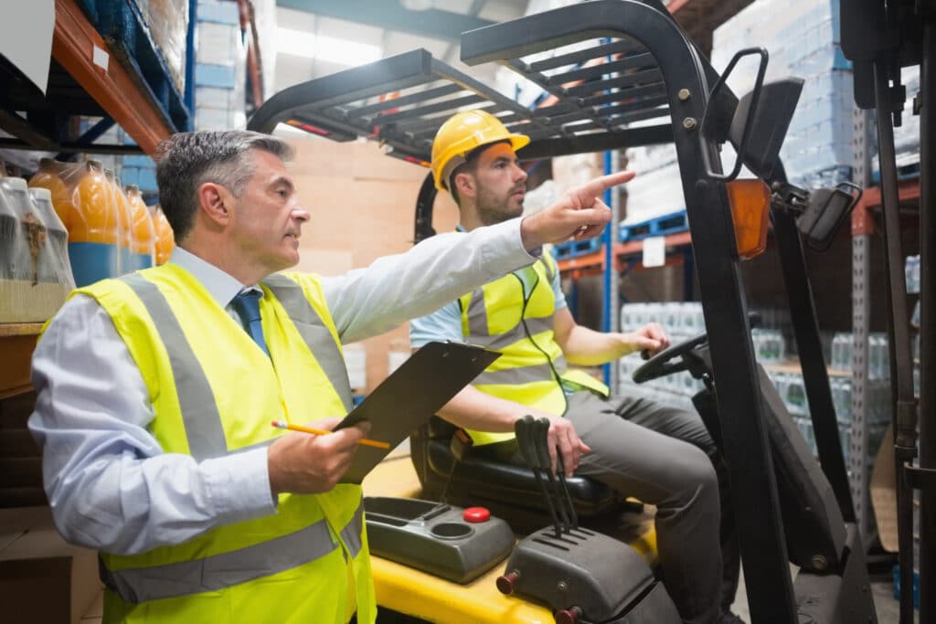 An instructor providing forklift training to a male delegate.